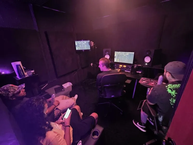 The desk working the session between the monitors, the room gathered behind