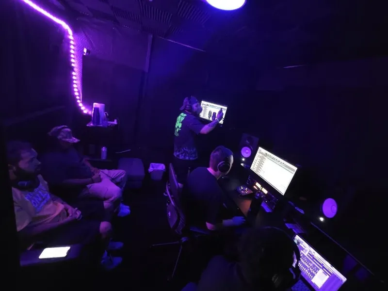 Full house under the string lights — the couch, the booth wall, and the desk all going