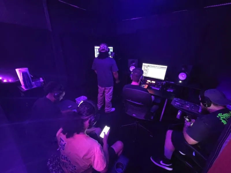 The take goes down — on the mic at the booth wall while the room listens in headphones